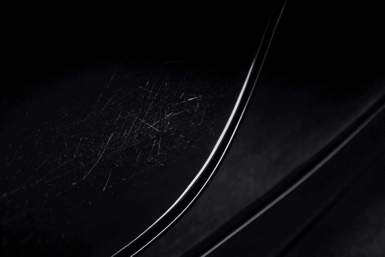 Macro close-up of light scratches on a black painted surface